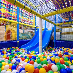 Kids playground indoor. Panoramic view inside the dry pool with colorful balls and slide. Nice plastic gym for activity in playroom. Children playground for sport and play in kindergarten.